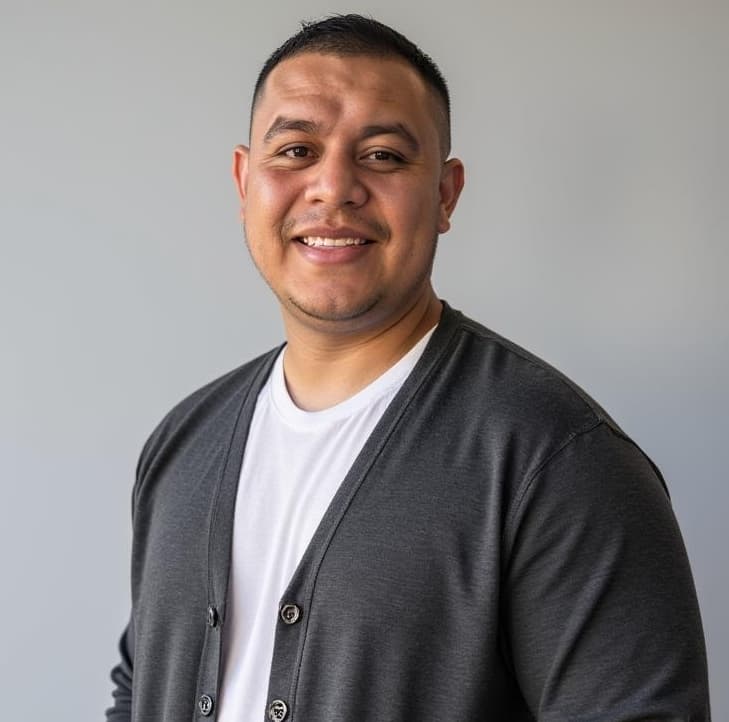 Smiling man with short dark hair wearing a white t-shirt and charcoal gray cardigan.
